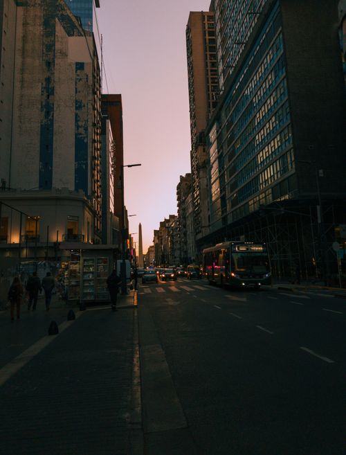 Free Vibrant city life on a busy street in Buenos Aires during sunset, showcasing urban architecture and city dwellers. Stock Photo
