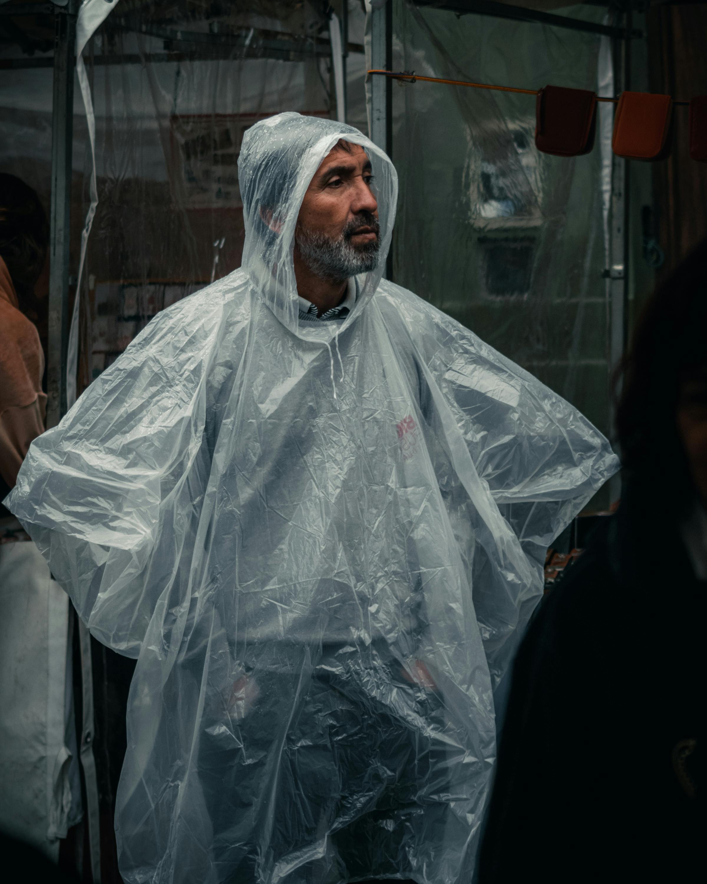 Adult man in a transparent raincoat standing outdoors in Buenos Aires on a rainy day.