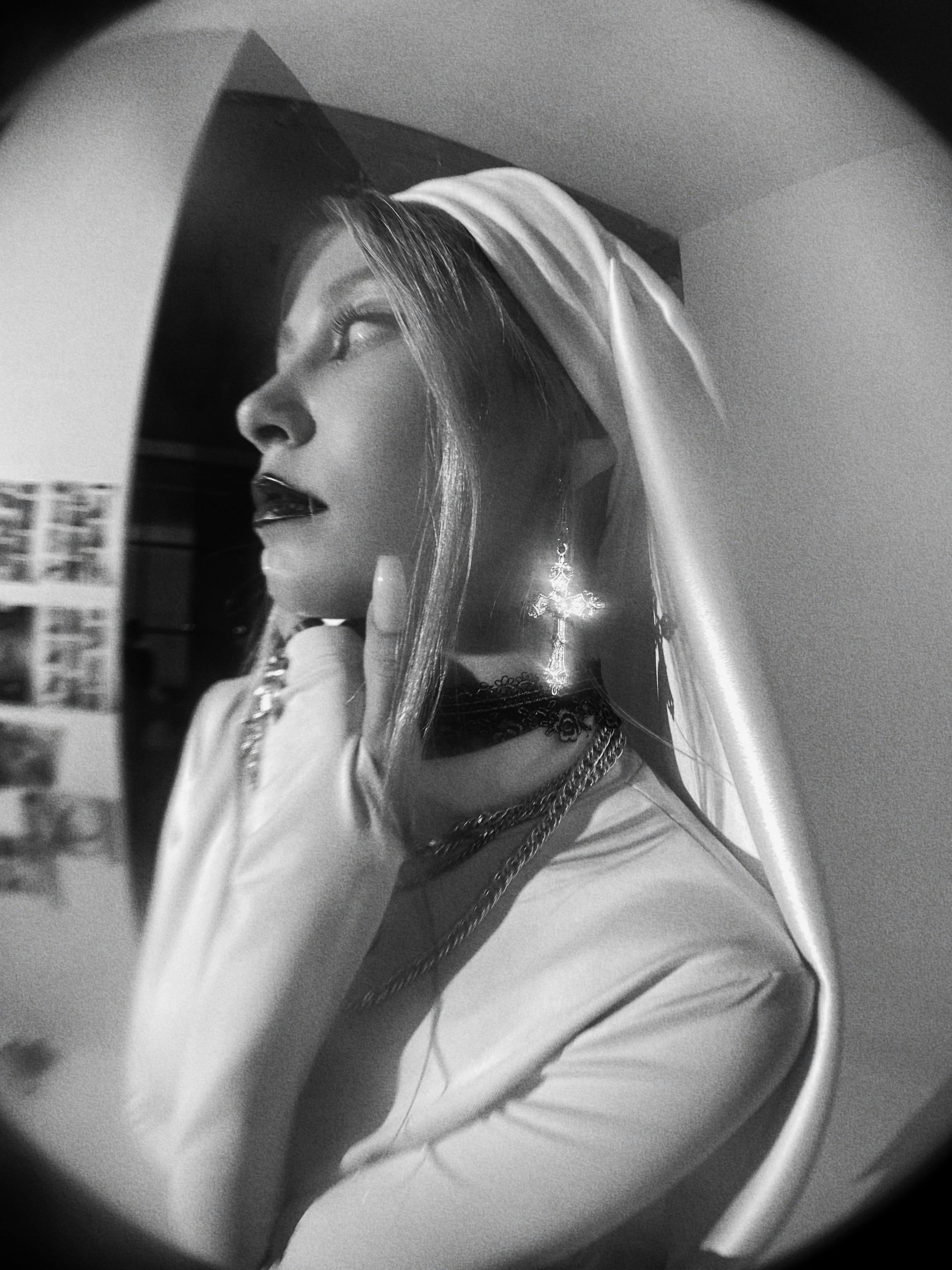 A dramatic black and white portrait featuring a woman in a headscarf and earring.