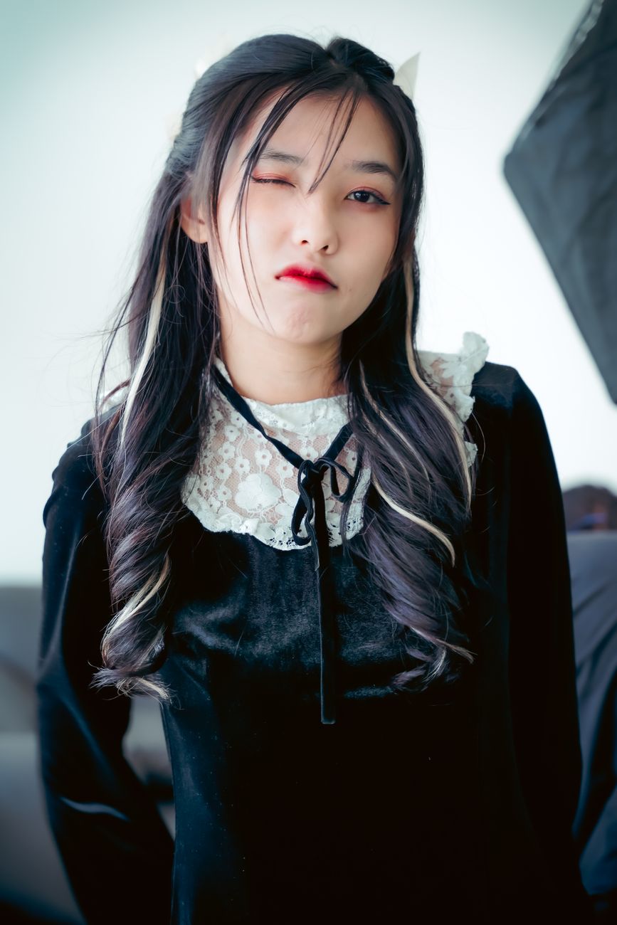 Portrait of a stylish teenager with red lipstick winking confidently indoors.