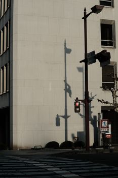 A city intersection with building shadows and traffic lights cast during sunset.
