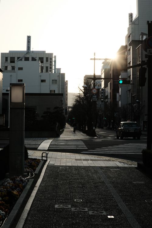 Free A tranquil urban street scene at sunset with dramatic lighting and shadows. Stock Photo