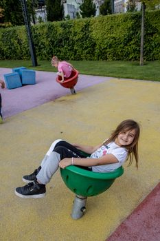 Two young girls having fun on a colorful outdoor playground in the sun.