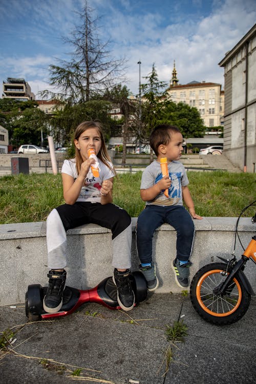 Children Sitting on Wall and Eating Ice Creams
