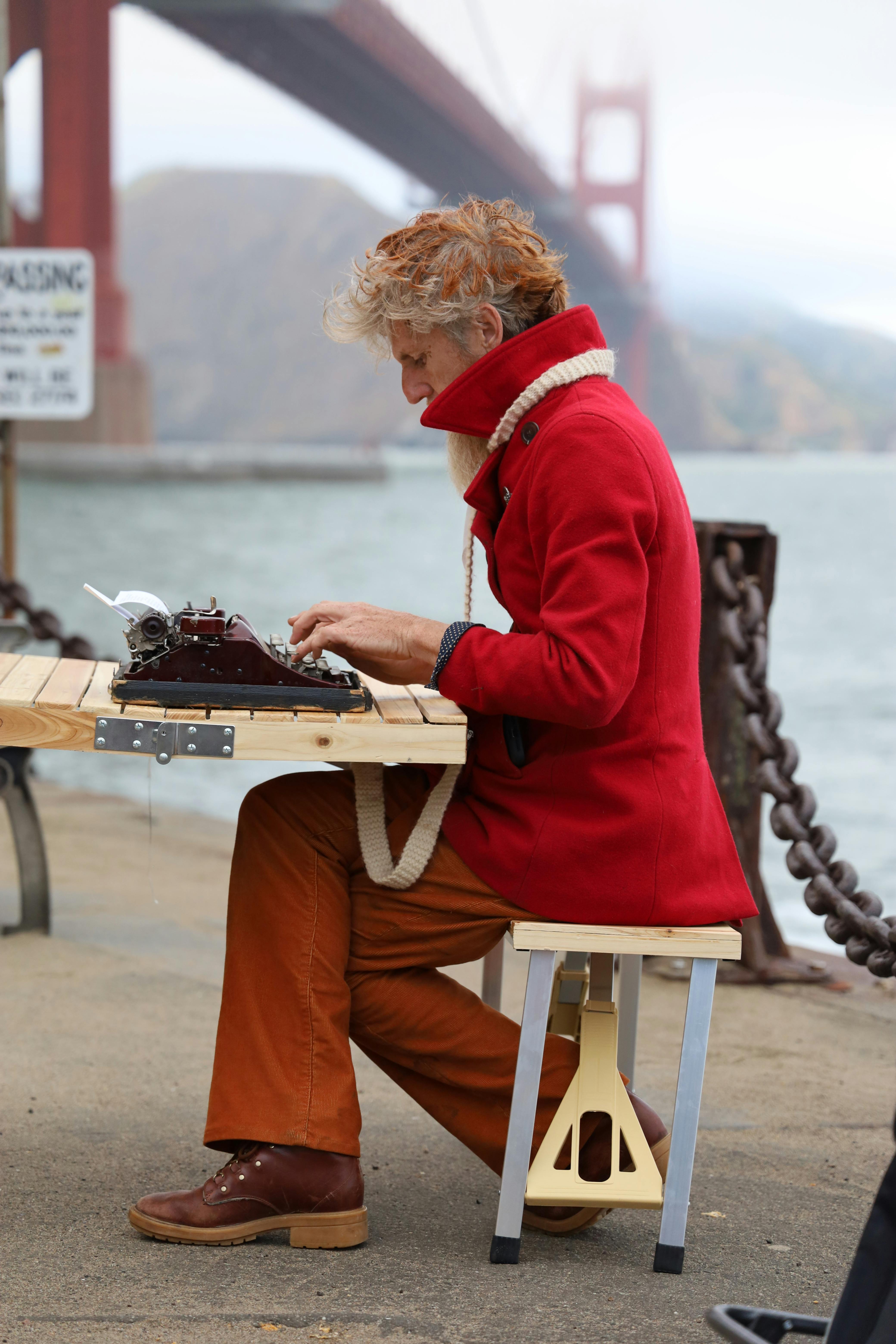 man in red suit jacket typing on typewriter by golden gate