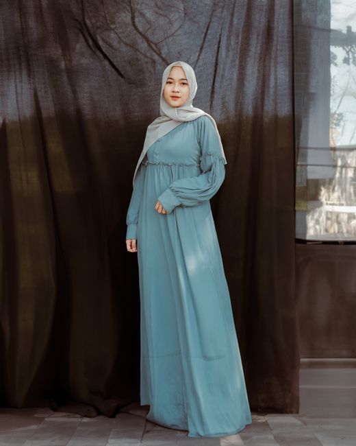 Elegant portrait of a woman wearing a hijab and traditional dress indoors.