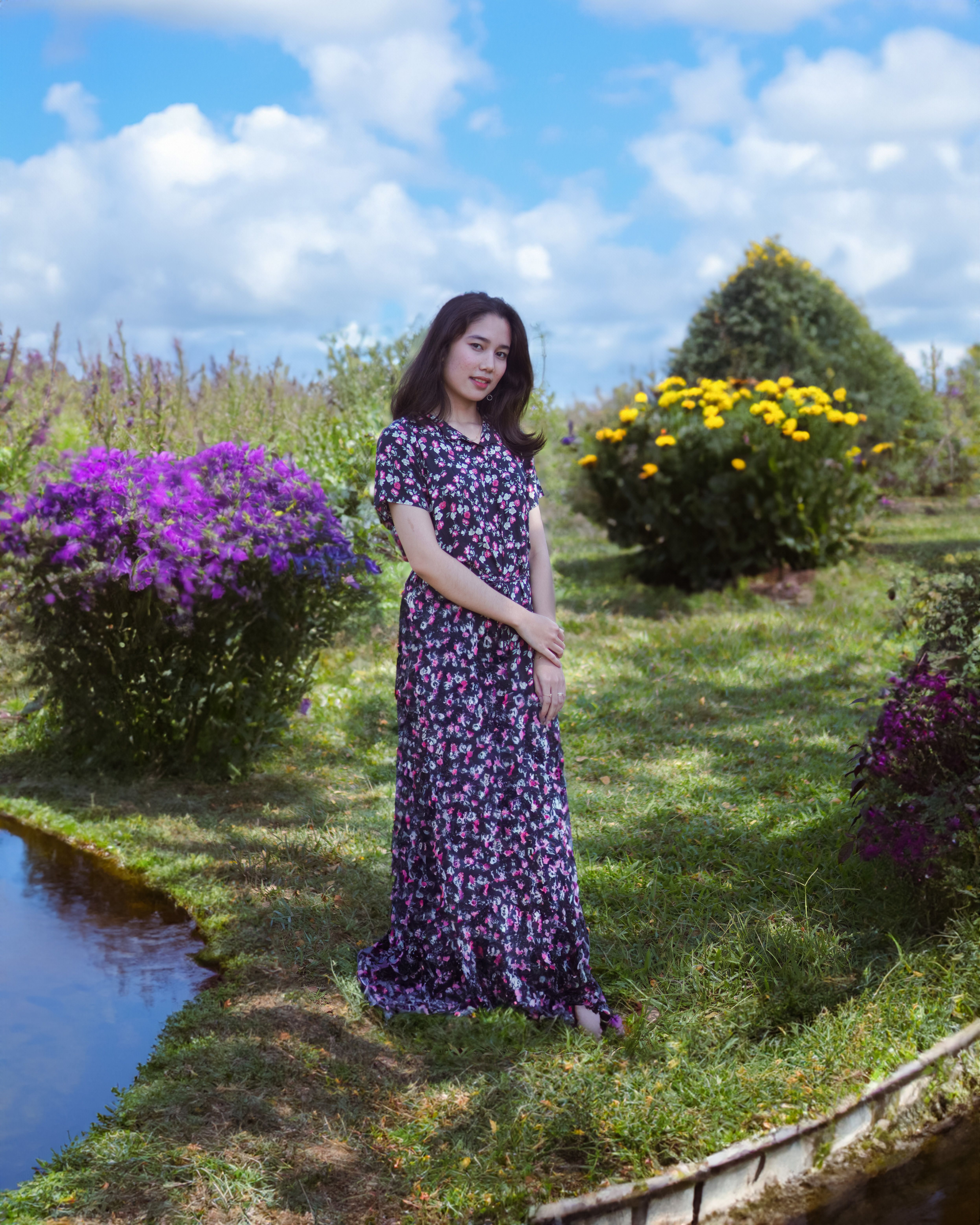 A woman in a floral dress standing in front of a pond · Free Stock Photo