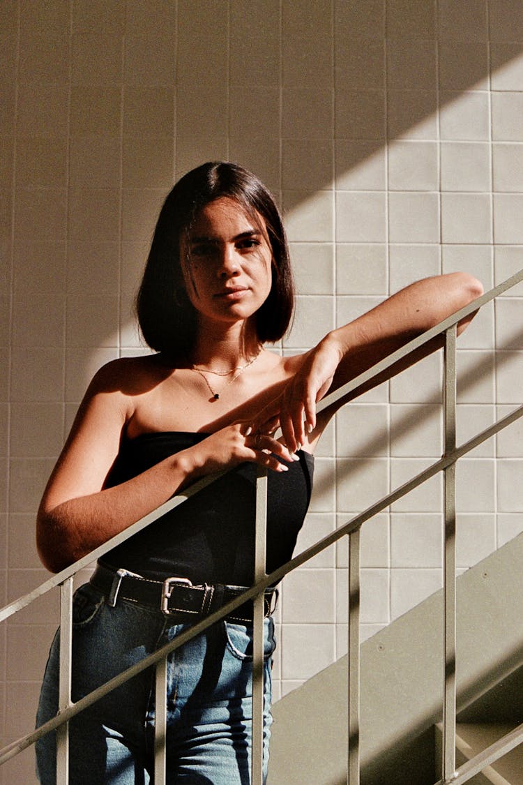 A Woman In Jeans And A Black Top Is Standing On A Stair