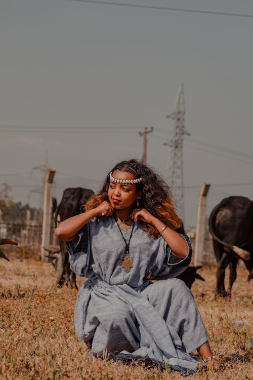 Woman Sitting in Blue Clothes and Posing in Village