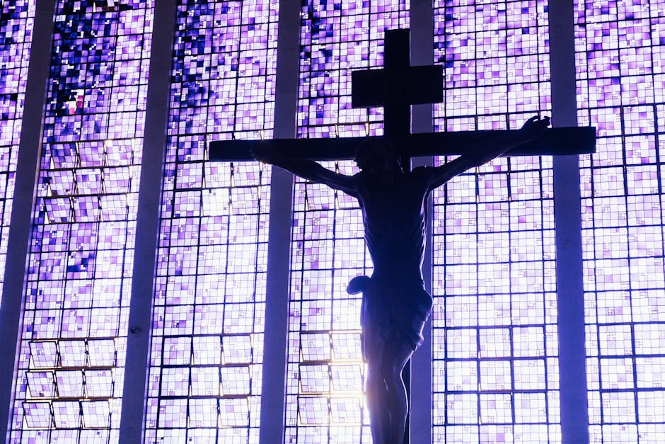 Dramatic silhouette of Jesus Christ crucifixion against vivid stained glass in Brasília church.