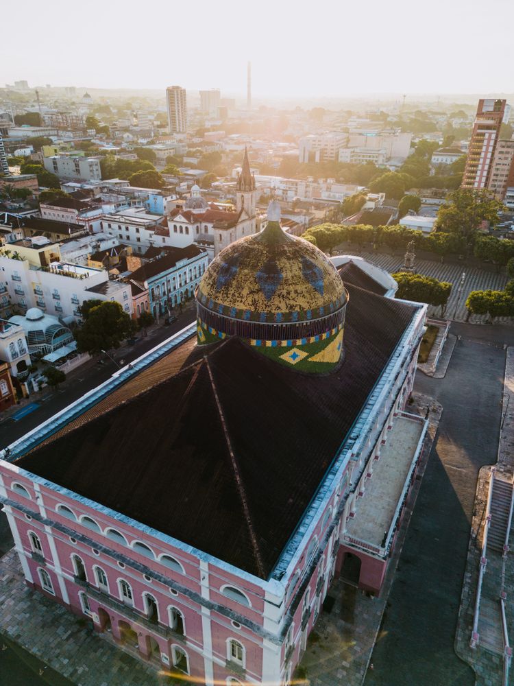 Aerial view of the pink Teatro Amazonas opera house in the historic center of Manaus at dusk.