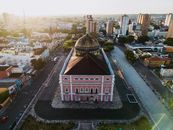 Aerial view of the iconic Teatro Amazonas in Manaus, Brazil, bathed in warm sunset light.