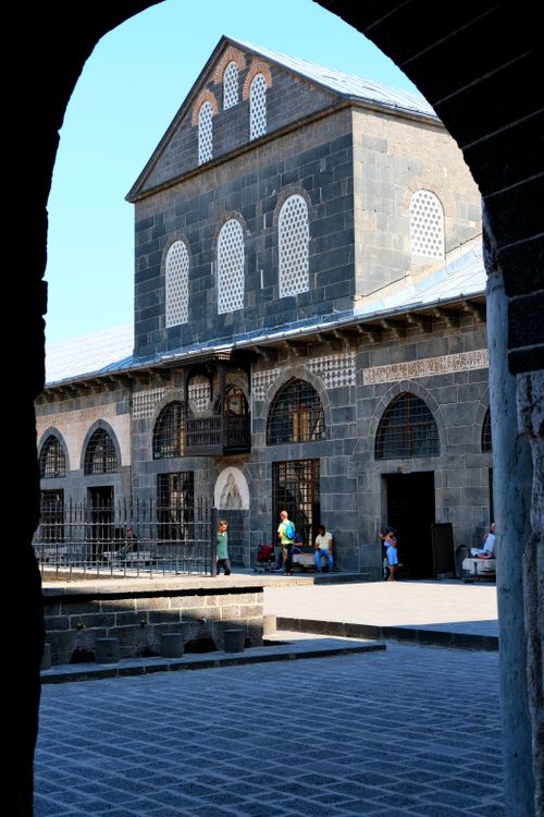 Free A view of Diyarbakır Grand Mosque's stone facade through an archway, showcasing historic architecture. Stock Photo