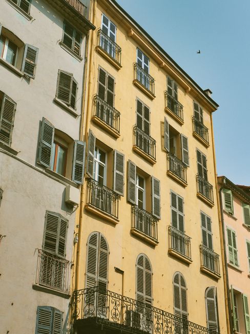 Vertical shot of colorful European apartment buildings with classic shutters and balconies.