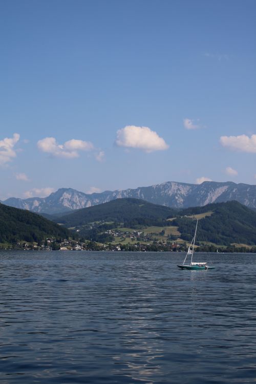 Free Peaceful sailboat on Attersee with scenic mountain backdrop in Austria. Stock Photo