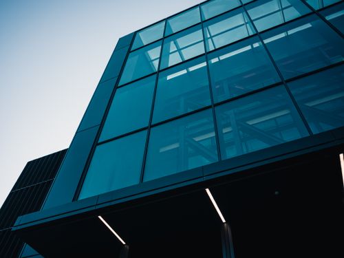 Free Low angle view of a modern glass building against a clear sky. Stock Photo