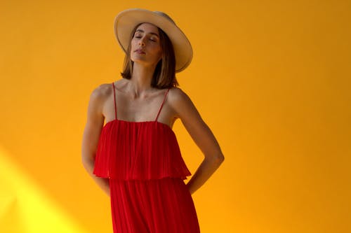 Woman in Red Dress and Straw Hat on Bright Yellow Background 