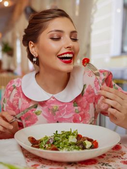 Smiling woman savoring a fresh salad indoors, creating a joyful and vibrant atmosphere.