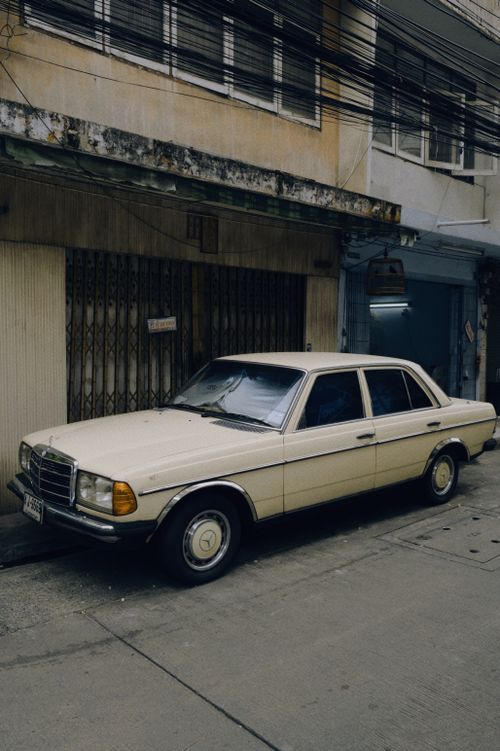 Free A classic beige Mercedes-Benz parked on a quiet urban street in a vintage setting. Stock Photo