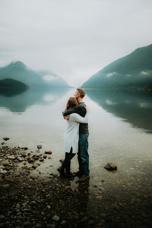 A Couple Standing on the Riverbank in a Mountain Valley 