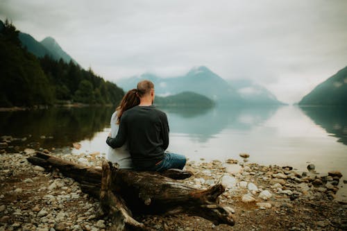 A Couple Sitting by the River in a Mountain Valley 