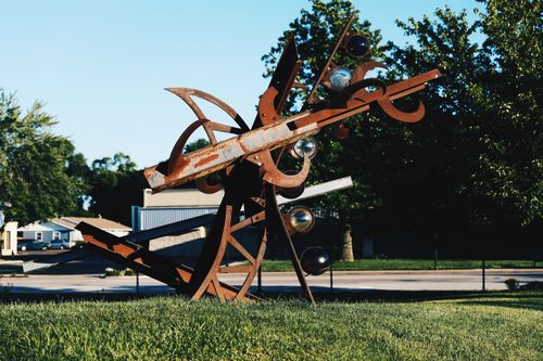 Free Rustic metal sculpture with abstract shapes and glass elements in a city park. Stock Photo