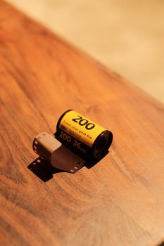 Close-up of a 35mm color film roll on a wooden table, evoking nostalgia.