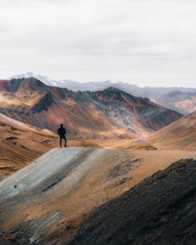 A lone adventurer standing amidst a stunning mountain panorama showcasing nature's grandeur.