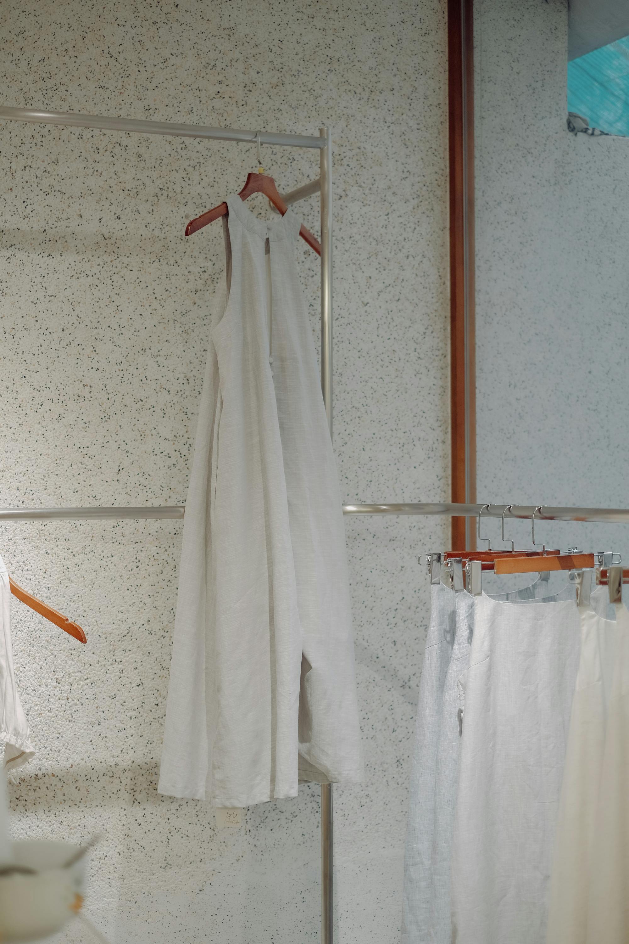 A stylish white dress elegantly hangs in a modern indoor clothing store setting.