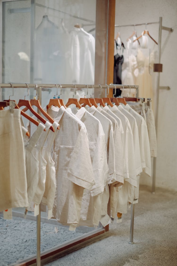 Clothes In Neutral Colors Hanging On The Racks In A Clothing Store 