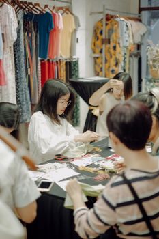 A group of women engaging in a collaborative sewing workshop, surrounded by textiles.