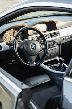 Close-up of sleek car interior featuring a steering wheel and dashboard controls.