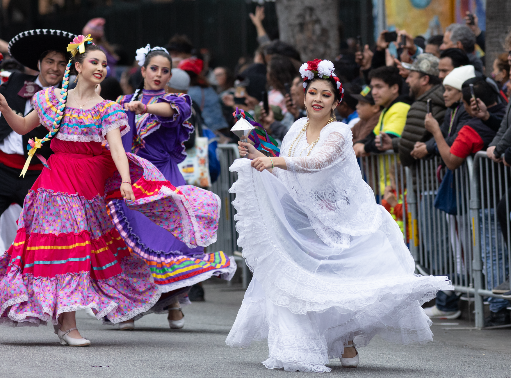 Colorful dancers in traditional attire perform at a bustling street festival.