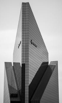 Black and white photo of a modern skyscraper in Ciudad de México with reflective glass surfaces.