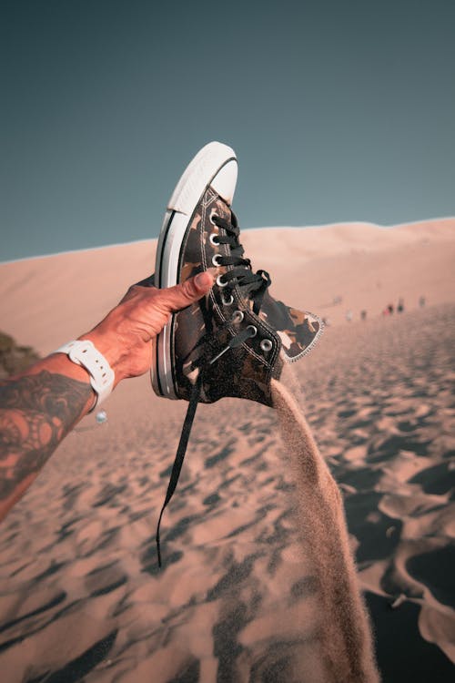 Man Hand Holding Shoe and Throwing Sand