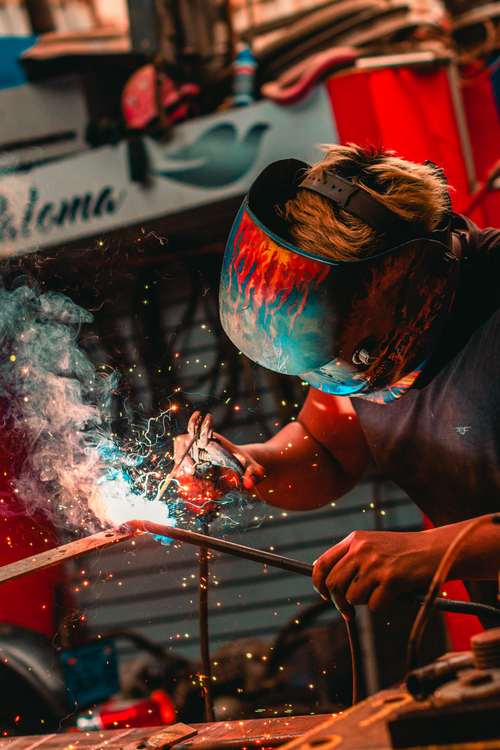 Free Close-up of a welder using safety gear and creating sparks in an industrial setting. Stock Photo