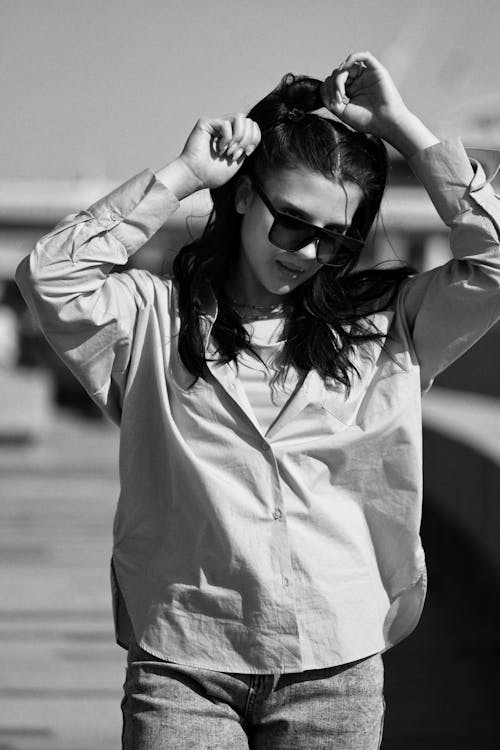 Black and White Shot of a Young Woman in a Casual Outfit Posing Outside 