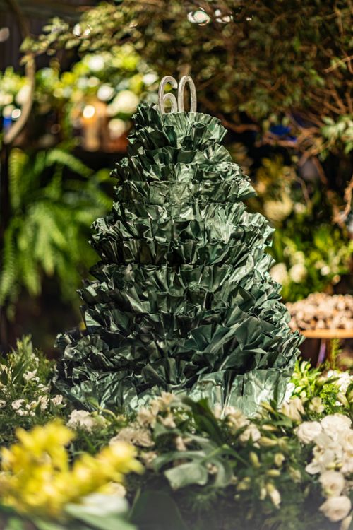Free A beautifully decorated greenery cake with '60' atop, surrounded by lush plants. Stock Photo