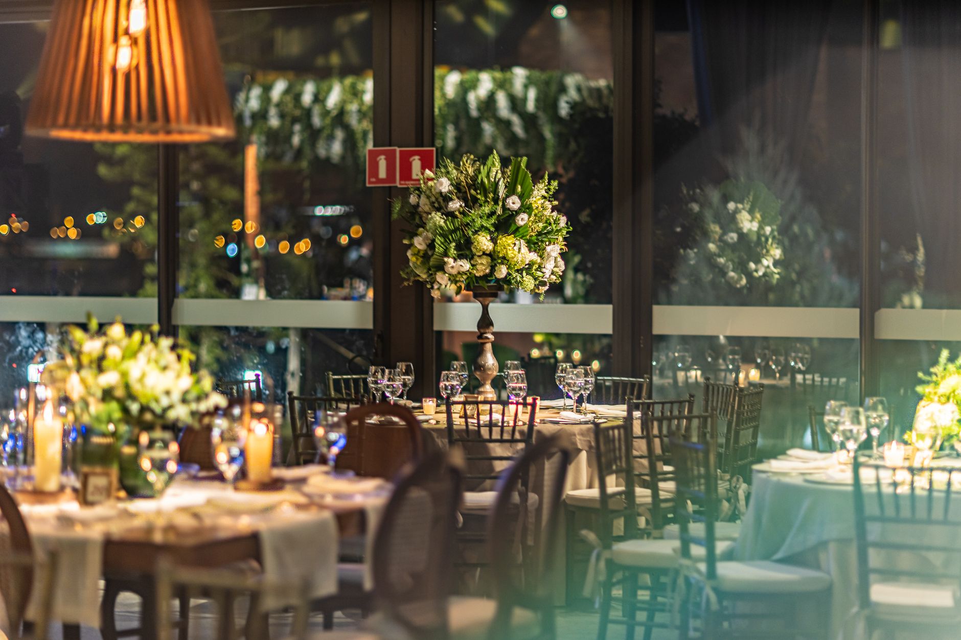A beautifully decorated indoor banquet hall with elegant flower arrangements and ambient lighting.