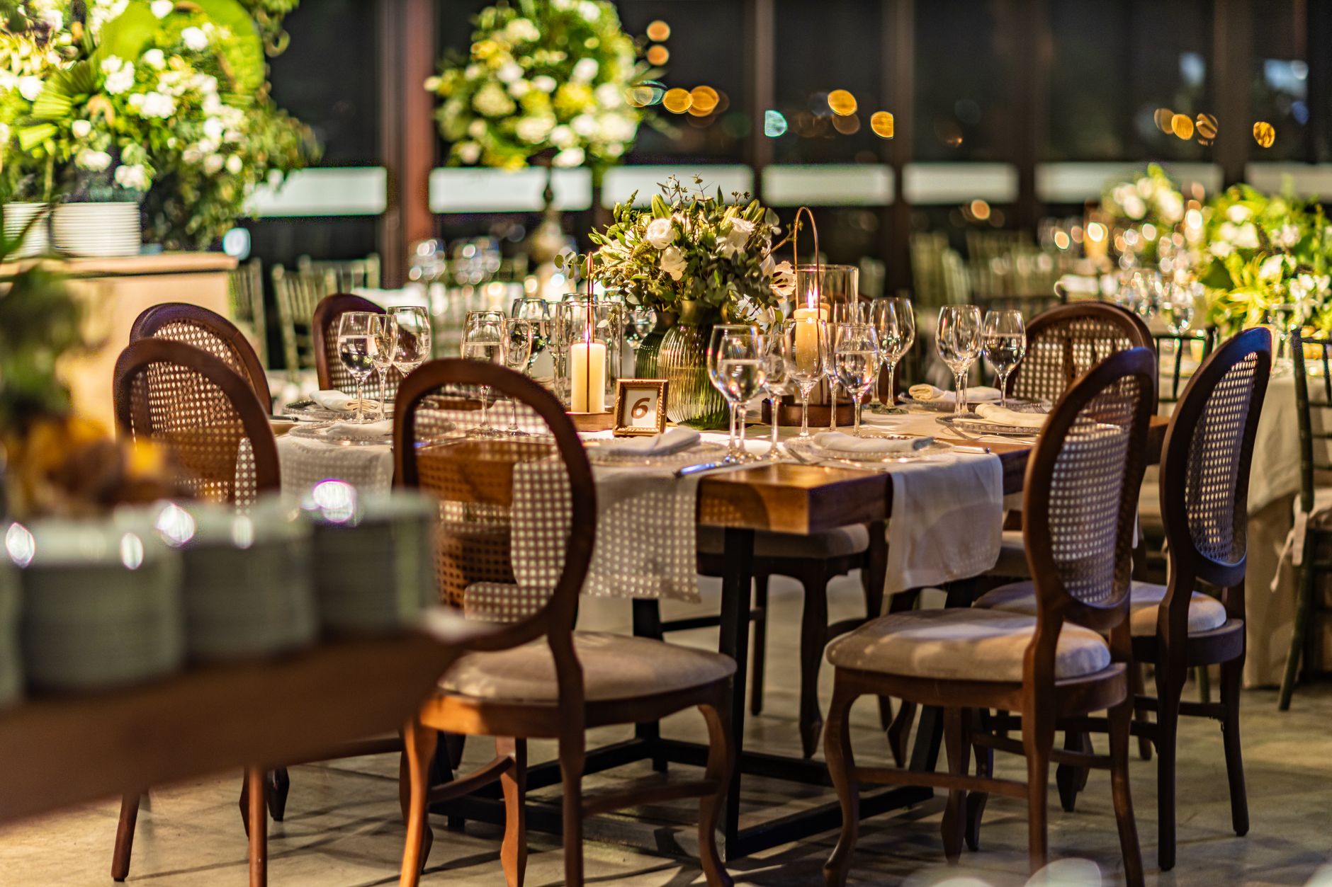 A beautifully arranged dining setup featuring floral centerpieces, candles, and elegant tableware for a special occasion.