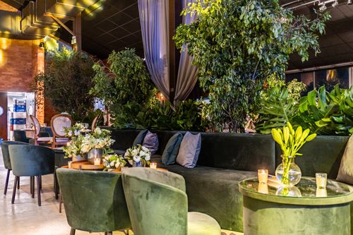 Free Sophisticated event venue featuring elegant seating, lush plants, and ambient lighting. Stock Photo