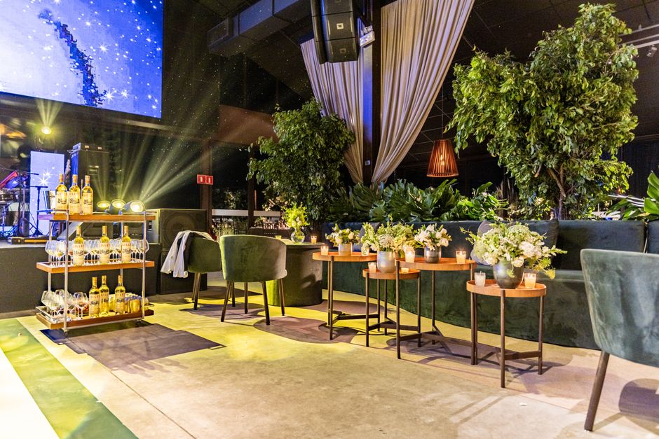 Sophisticated indoor event venue featuring lush plants, bar cart, and cozy seating arrangements.