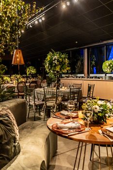 Chic restaurant interior decorated for a celebration with lush greenery and stylish table settings.