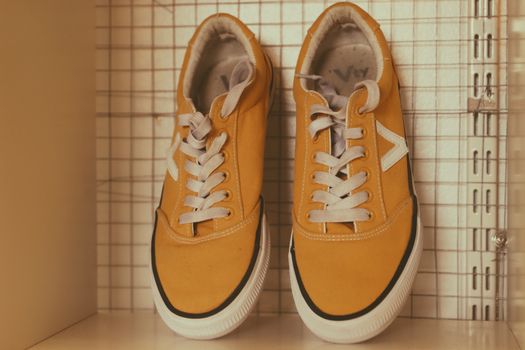 Pair of Yellow Sneakers Standing on a Shelf