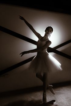 A graceful ballet dancer captured in dramatic black and white lighting, displaying poise and elegance.