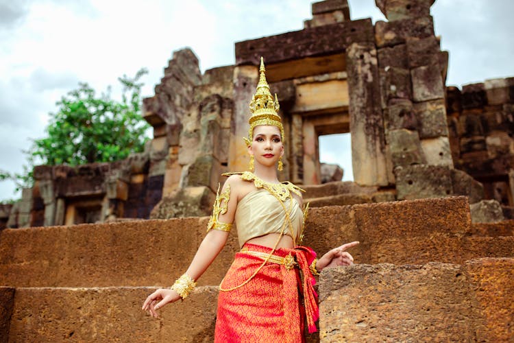 Woman In A Traditional Costume Standing In Front Of A Temple 