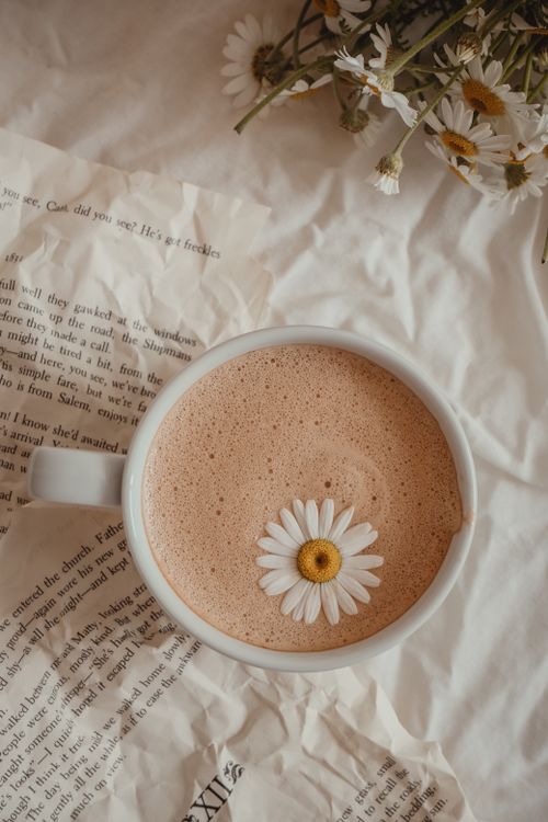Free Top view of a coffee cup with a daisy flower on rustic paper background. Perfect for lifestyle and floral themes. Stock Photo