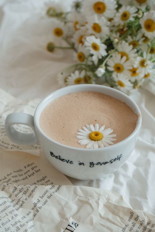 Free A cozy shot of a coffee cup with 'Believe in yourself' printed, garnished with a daisy. Stock Photo