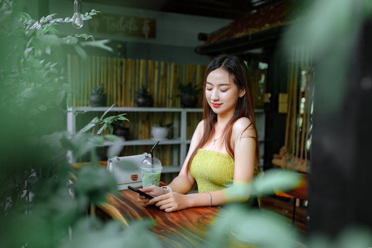 Young Woman Looking At Her Phone In A Cafe