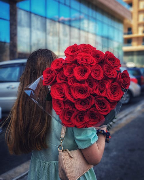 Woman on Street Holding Bouquet of Red Roses